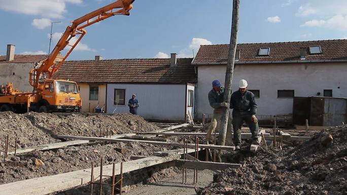 建筑工人正在拉着大软管进行混凝土浇筑