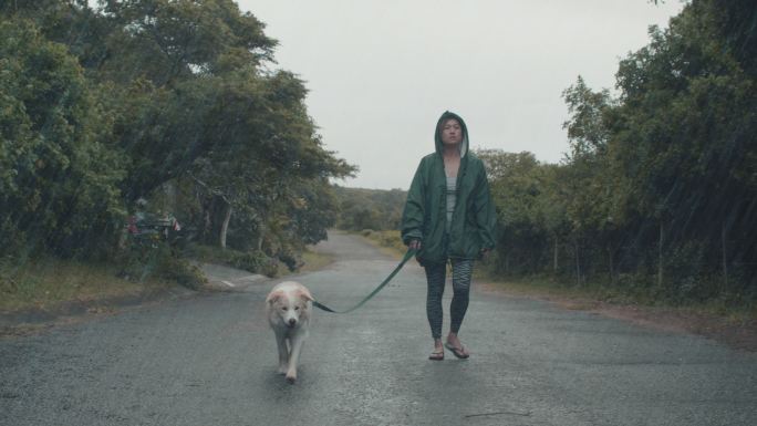 一个女人带着她的狗在雨中散步