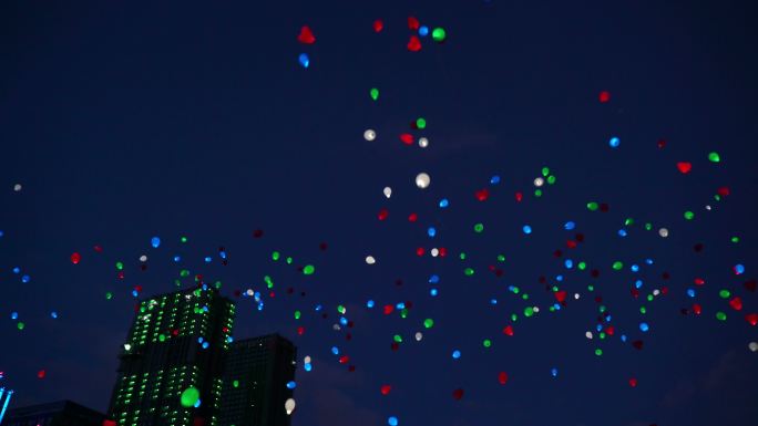在夜晚城市的天空中飞行的彩色气球