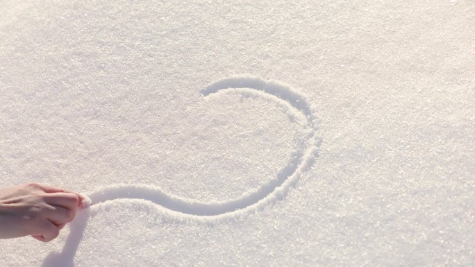 女性在雪上手绘心形图案