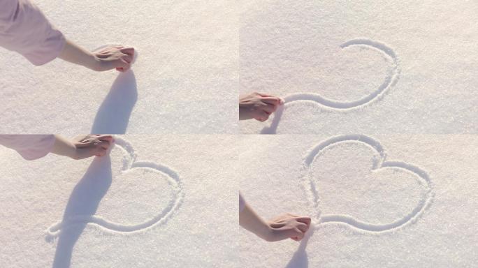 女性在雪上手绘心形图案