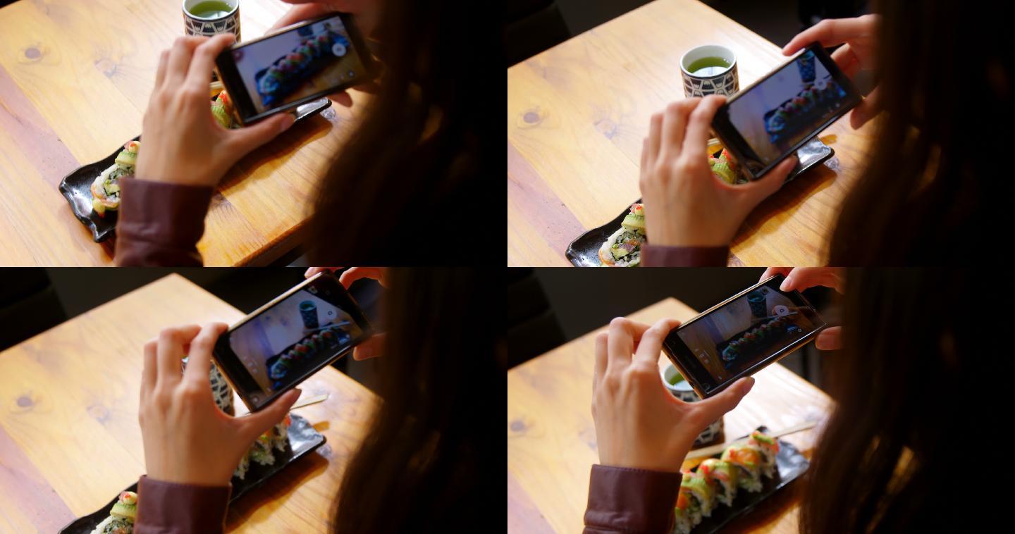 在餐厅用手机拍寿司的女人