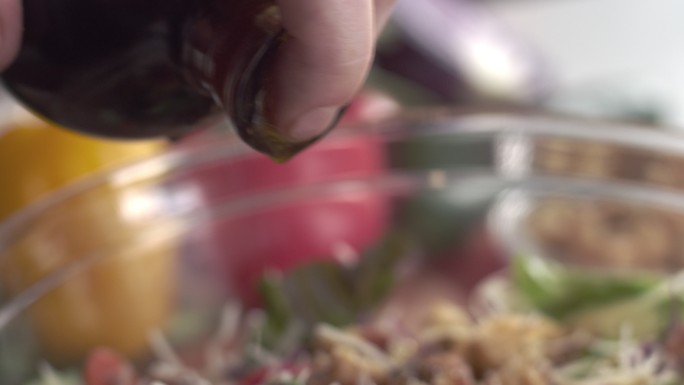 厨师用油和醋调味新鲜的田园沙拉的特写镜头