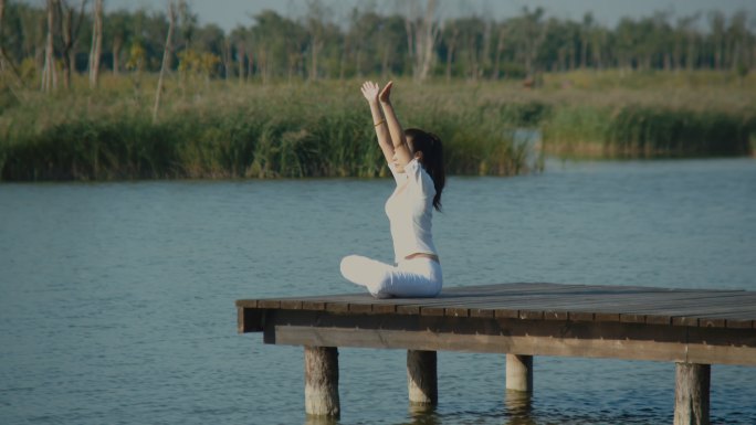 在湖畔栈桥练习瑜伽的女人