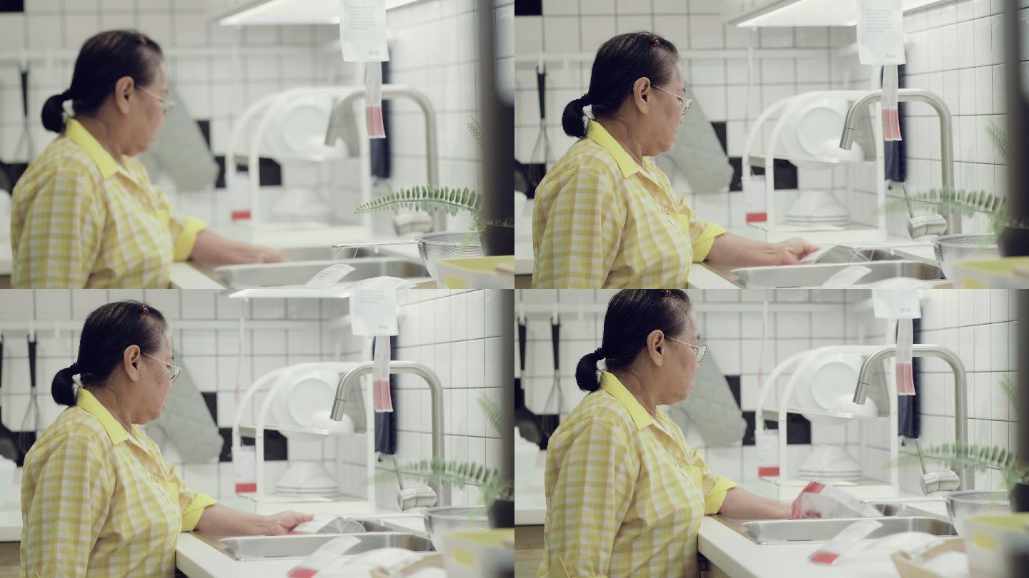 亚洲高级妇女看零售展示的厨房用品