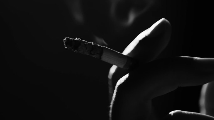 手指间燃烧过半的香烟特写