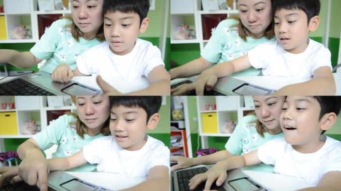 妈妈在教她的儿子使用笔记本电脑