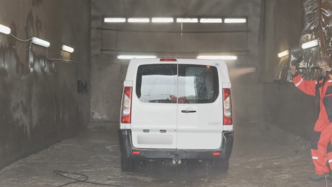洗车工用一股水冲洗汽车。