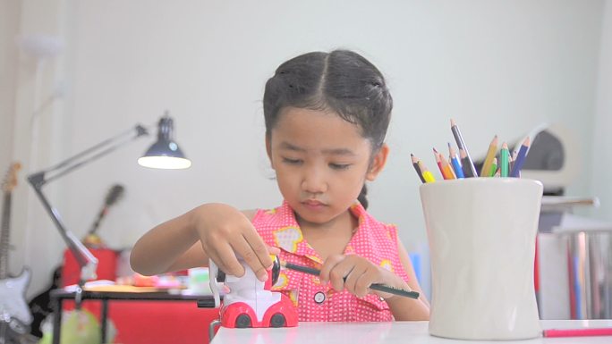 亚洲小女孩用彩色卷笔刀