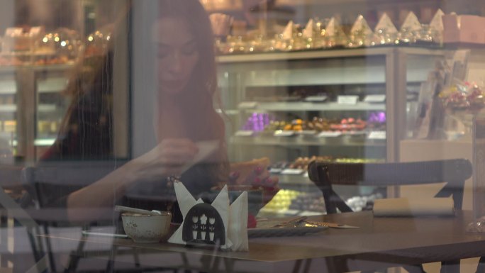 漂亮的黑发年轻女子在糕点店吃蛋糕