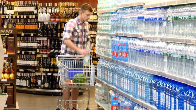 年轻人推着购物车在超市买水