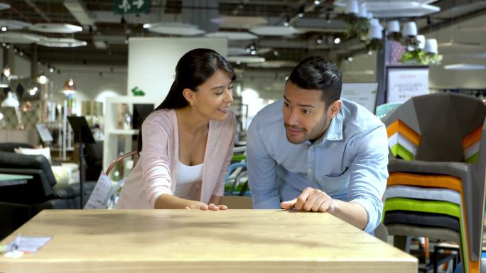 夫妇在一家家具店看着一张木制餐桌