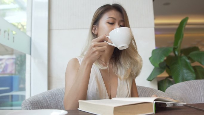 女孩一边看书一边喝咖啡。