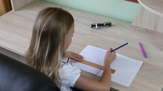 小女孩在笔记本上用尺子和铅笔画线
