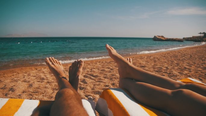 一对夫妇躺在海滩蜜月旅行海滨度假日光浴