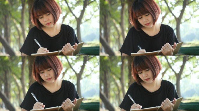 在公园里写日记的年轻亚洲女人