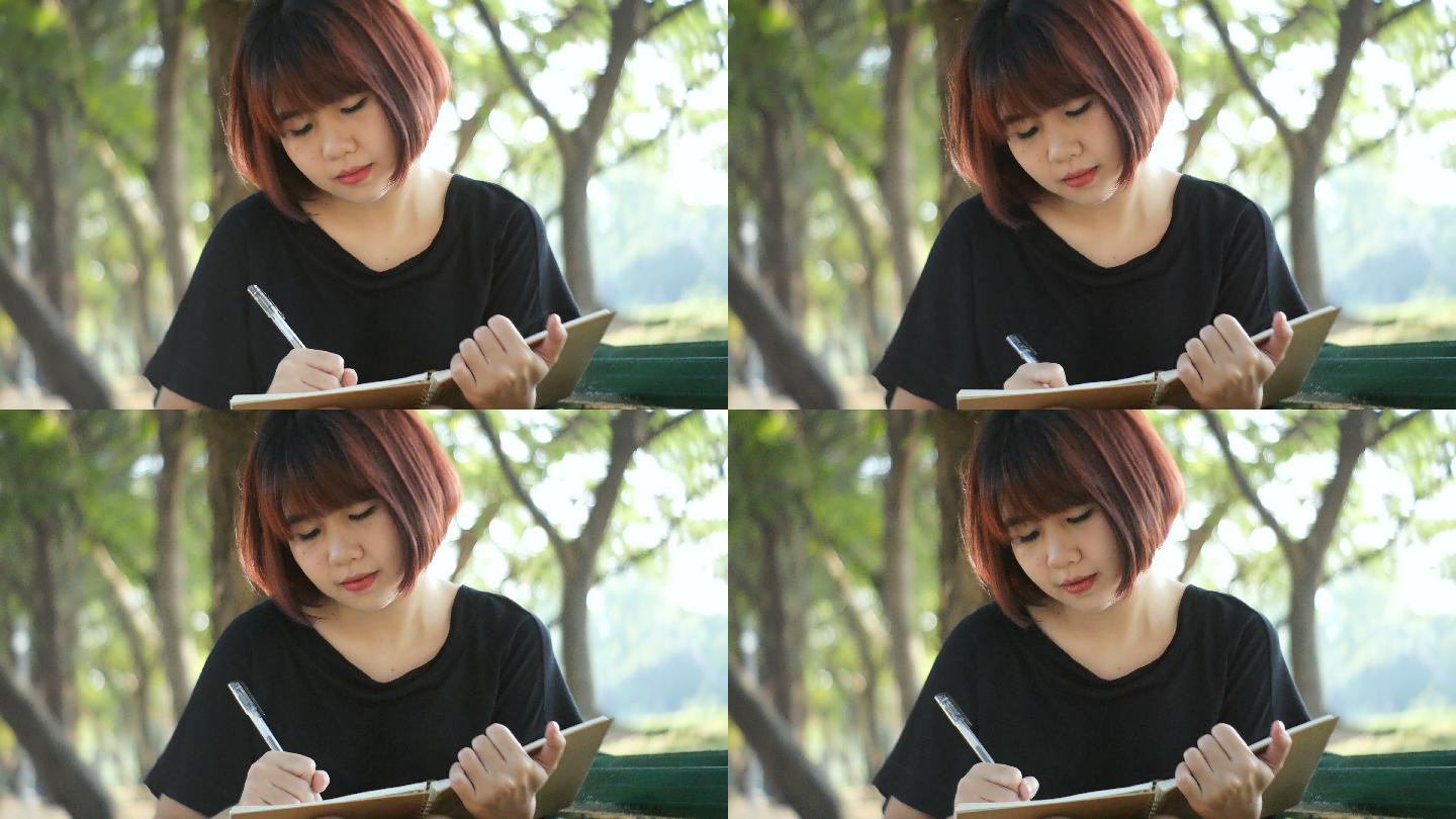 在公园里写日记的年轻亚洲女人