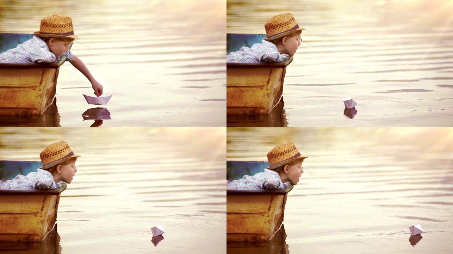 男孩把一只纸船放在水面上吹它走