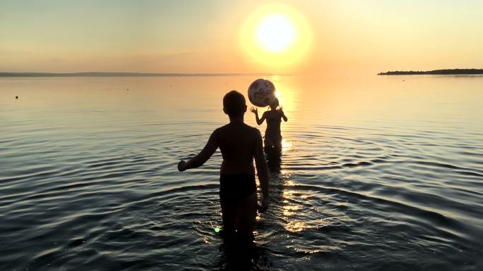 日落时孩子们在水里玩球