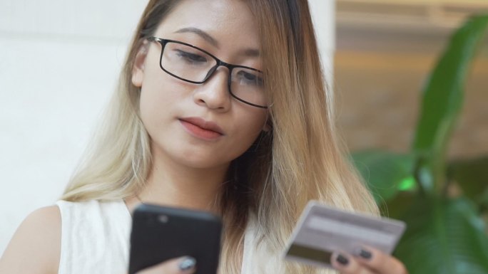 女人用手机用信用卡在线购物