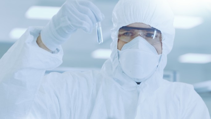 科学家穿着防护服拿着装有实验药物的试管