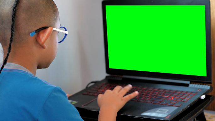 小男孩在玩绿色屏幕笔记本电脑