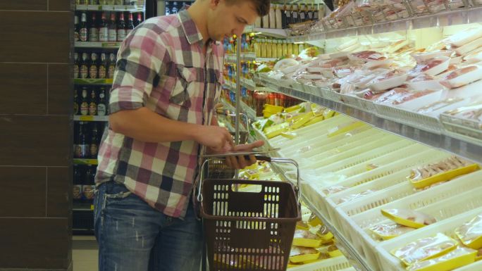 人们推着购物车在超市购买冷藏食品