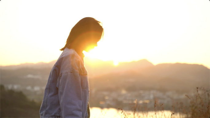 黄昏时分女孩在山顶散步，逆光唯美少女剪影