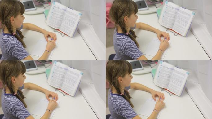 一个十几岁的女孩坐在桌子旁做作业