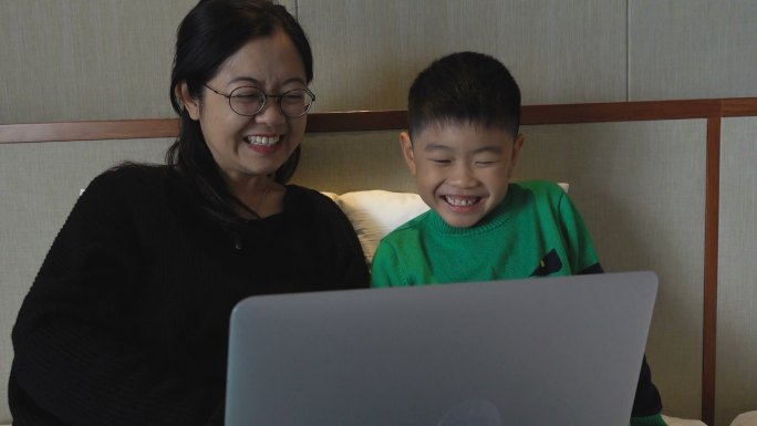 母亲和儿子在床上使用电脑