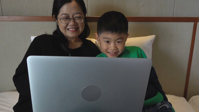 母亲和儿子在床上使用电脑