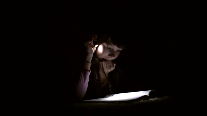 小女孩用手电筒看书