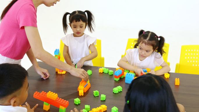 老师与学生一起玩彩色积木玩具的场景