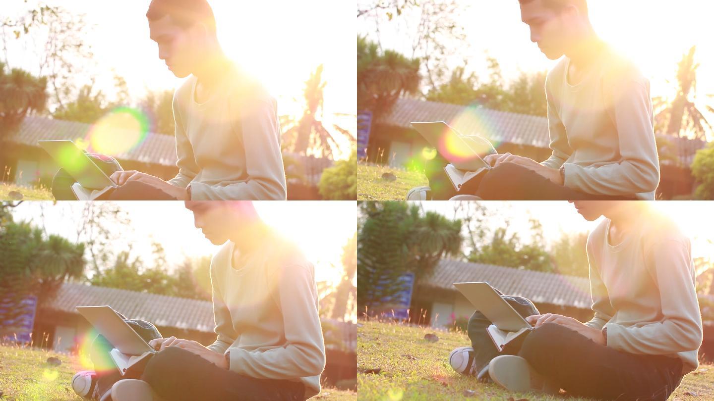 男孩坐在草坪上学习