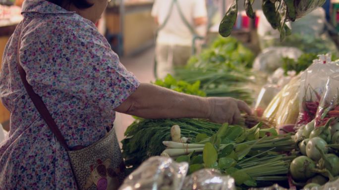 妇女在农贸市场选择新鲜蔬菜
