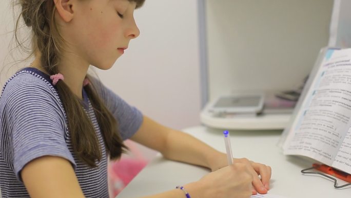 一个十几岁的女孩坐在桌子旁做作业