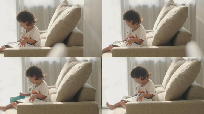 坐在沙发上看书的小男孩。