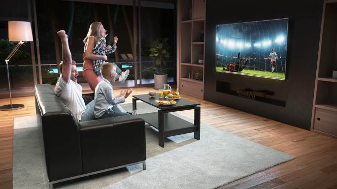 一家人坐在客厅的沙发上看电视上的足球节目