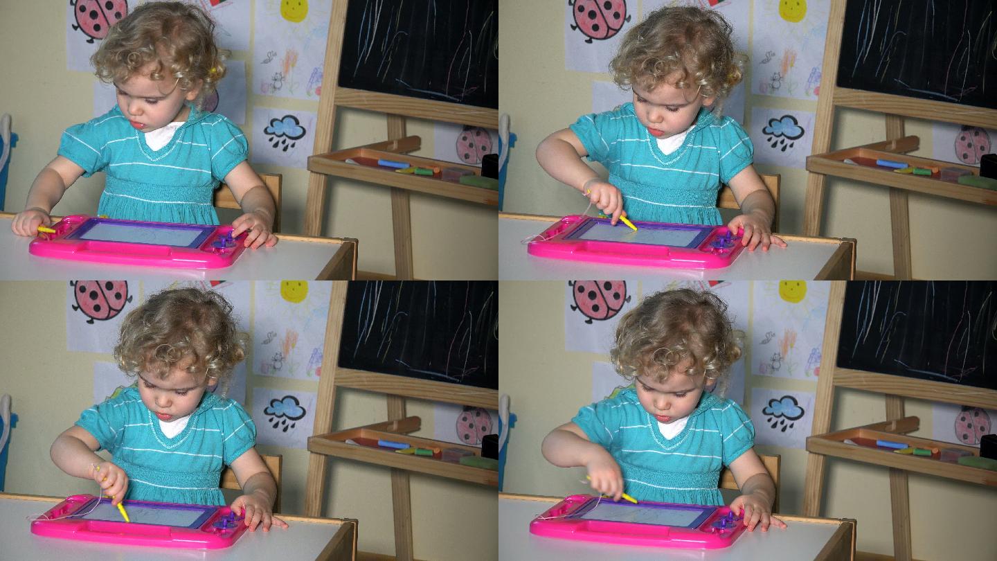 小女孩坐在磁铁板旁画画。静态的镜头。