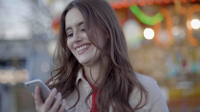 一个年轻女子微笑看着智能手机，