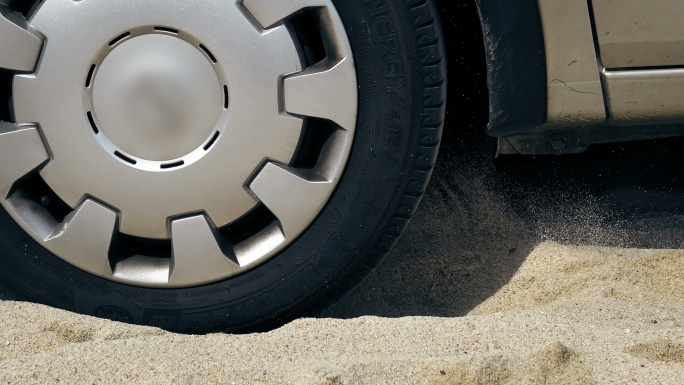 一辆汽车的转轮陷在沙滩上的沙子里