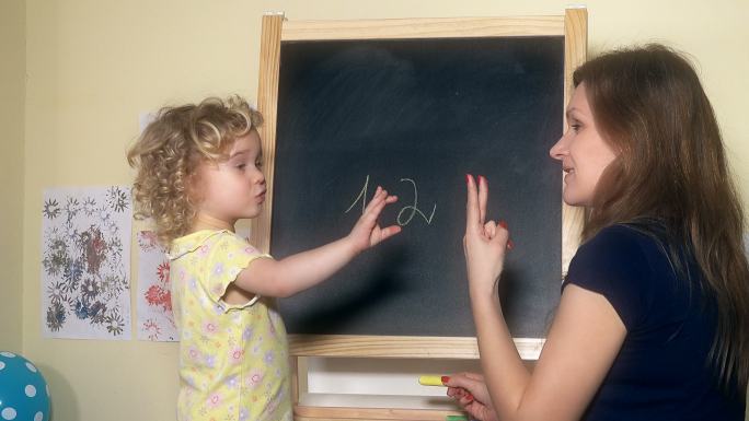 女教师在黑板上给小女孩写数字