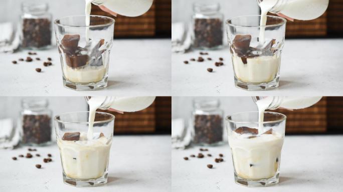 慢镜头将牛奶倒入加冰的咖啡杯中。