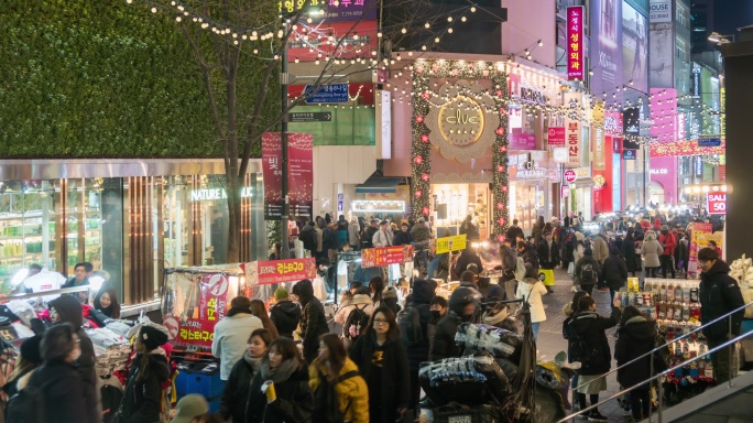 一群亚洲人走在韩国明洞的人行道上购物