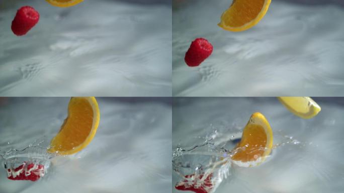 橘子和覆盆子掉进水中溅起水花。高速摄影机