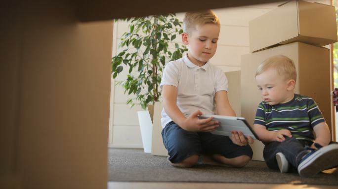 小男孩在他们的新房子玩或阅读平板电脑