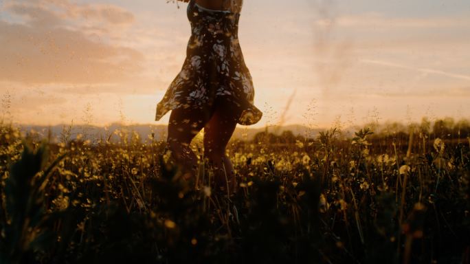 女人旋转在日落的田野中央