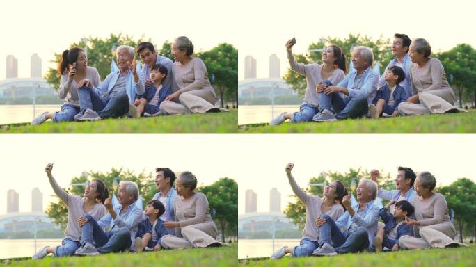 幸福的三代亚洲家庭坐在户外草地上自拍