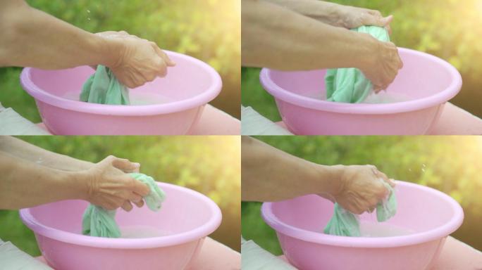 女人的手在一个粉红色的塑料碗里洗衣服