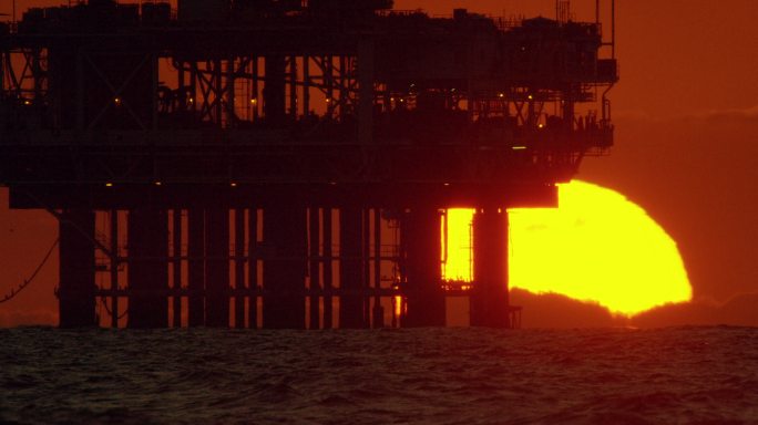 日落在地平线上的石油钻井平台